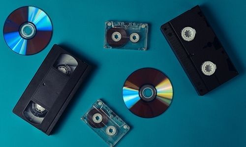 CDs and cassette tapes on a blue background arranged diagonally