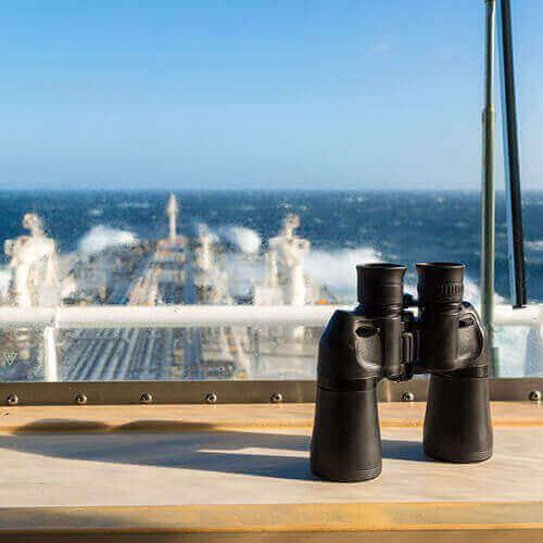 Binoculars on a boat deck overlooking the ocean wake