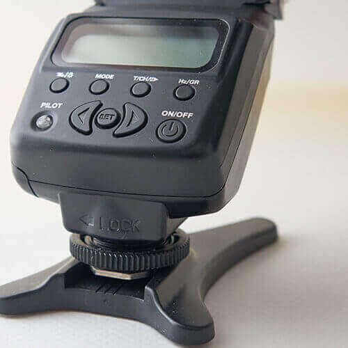 Black camera flash unit mounted on a swivel stand against a white background