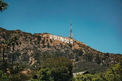 Iconic white Hollywood Sign on green hills under bright blue sunny sky