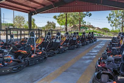 MB2 Raceway indoor karting track in Santa Clarita, with sleek black-and-red karts speeding through banked turns under neon lights