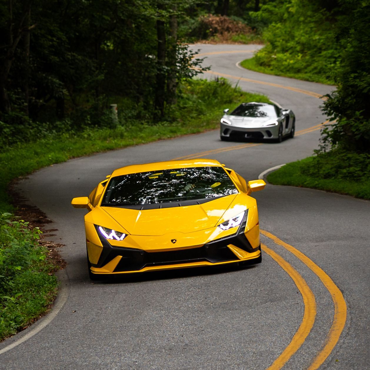 Two sports cars are driving down a curvy road