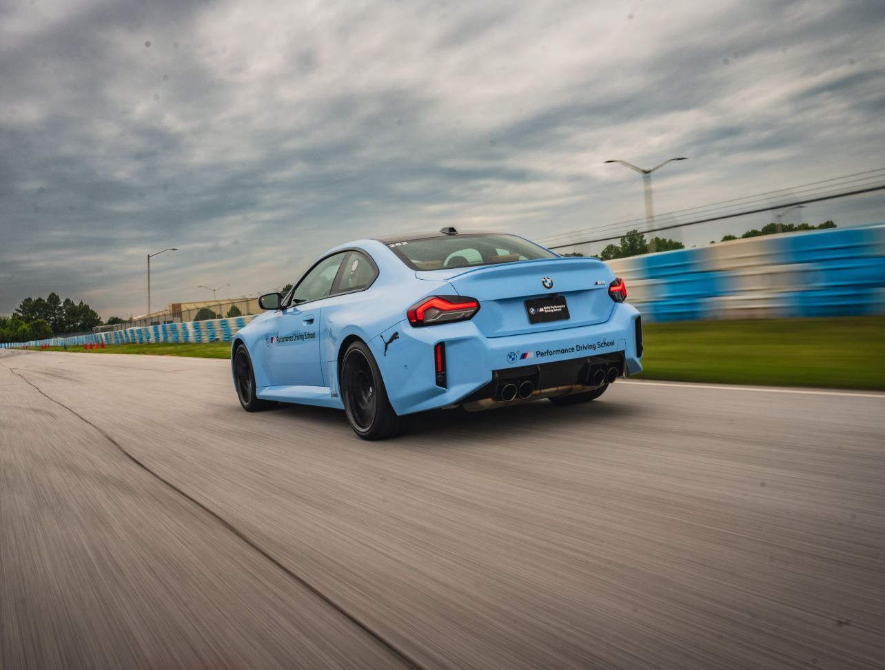 A blue sports car is driving down a race track
