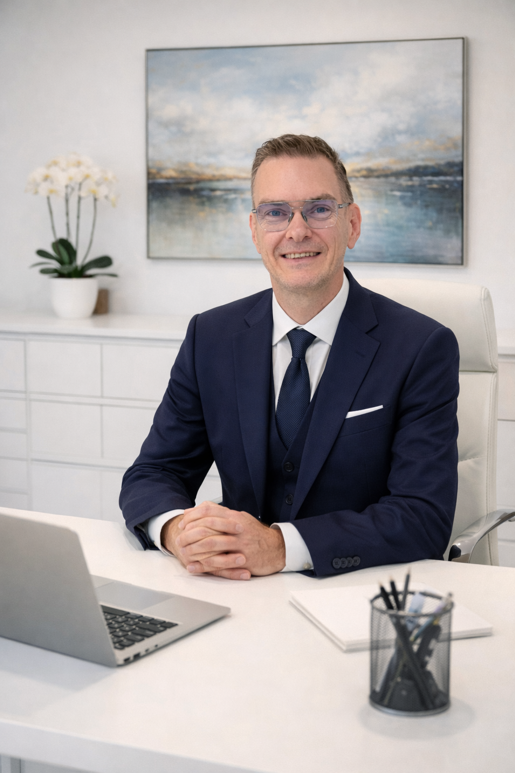 Holger Freerks im dunkelblauen Anzug an seinem Schreibtisch