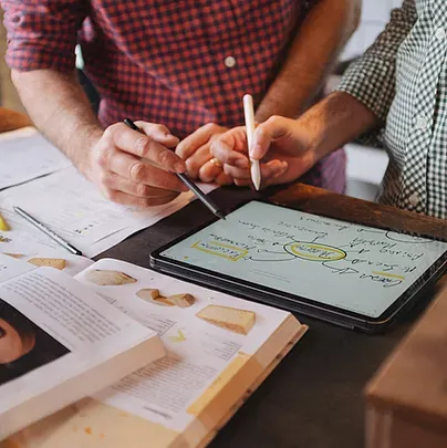 Dois homens estão sentados à mesa escrevendo em um tablet.
