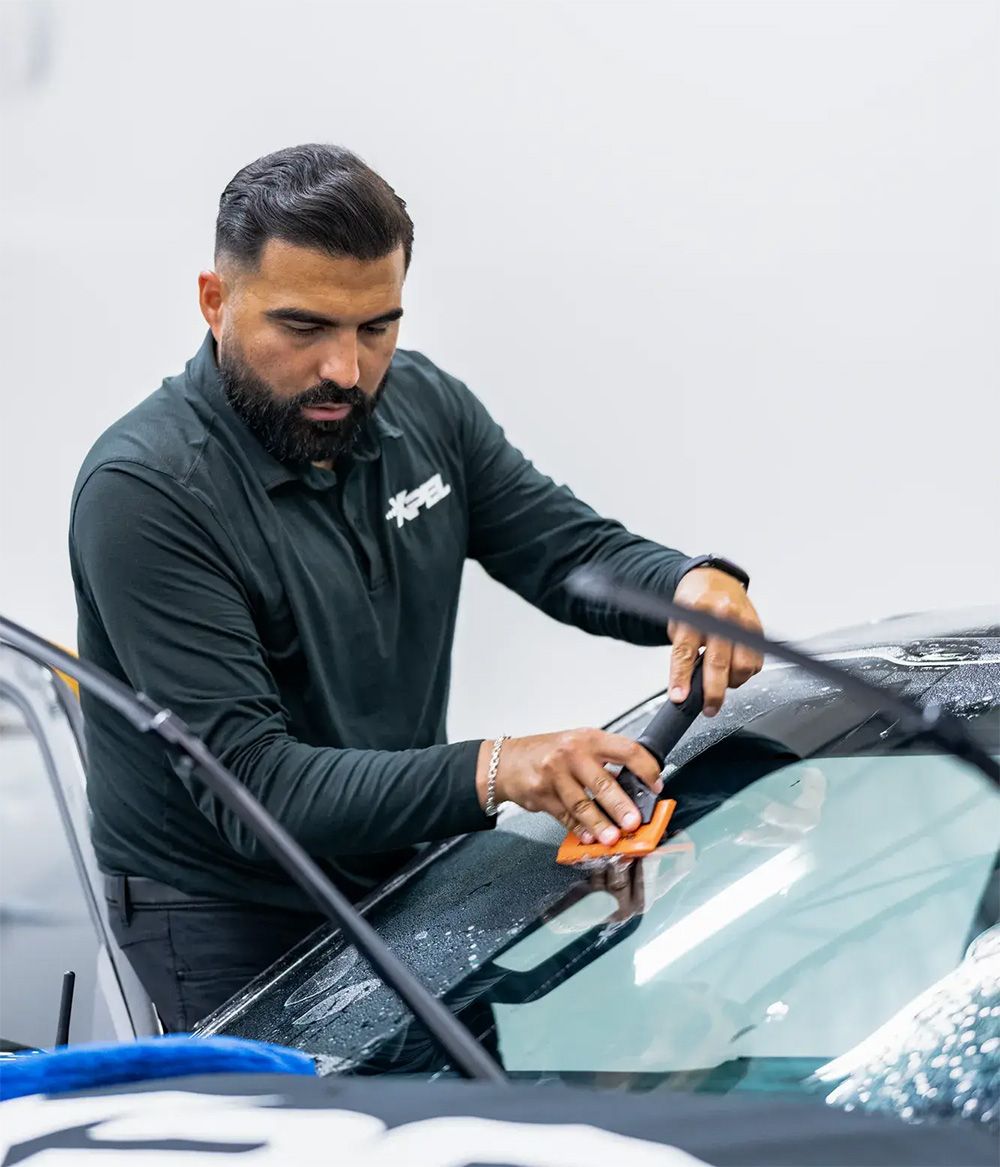 A man is installing window tint to a car