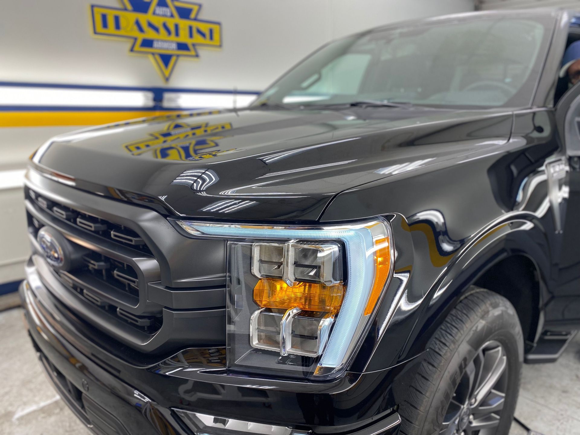 A black ford truck is parked in front of a sign that says hansen 's