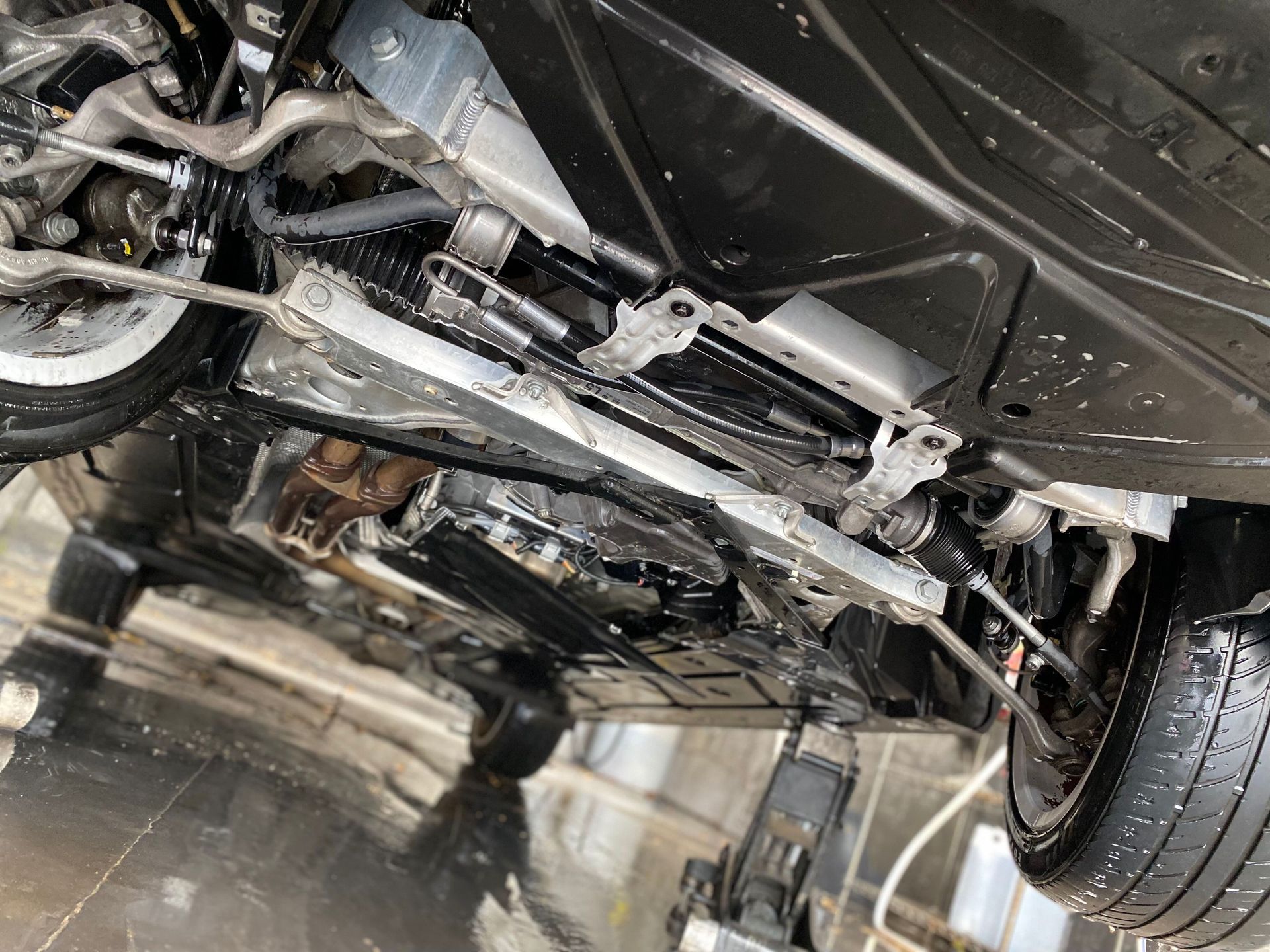 The underside of a car is being cleaned in a car wash.