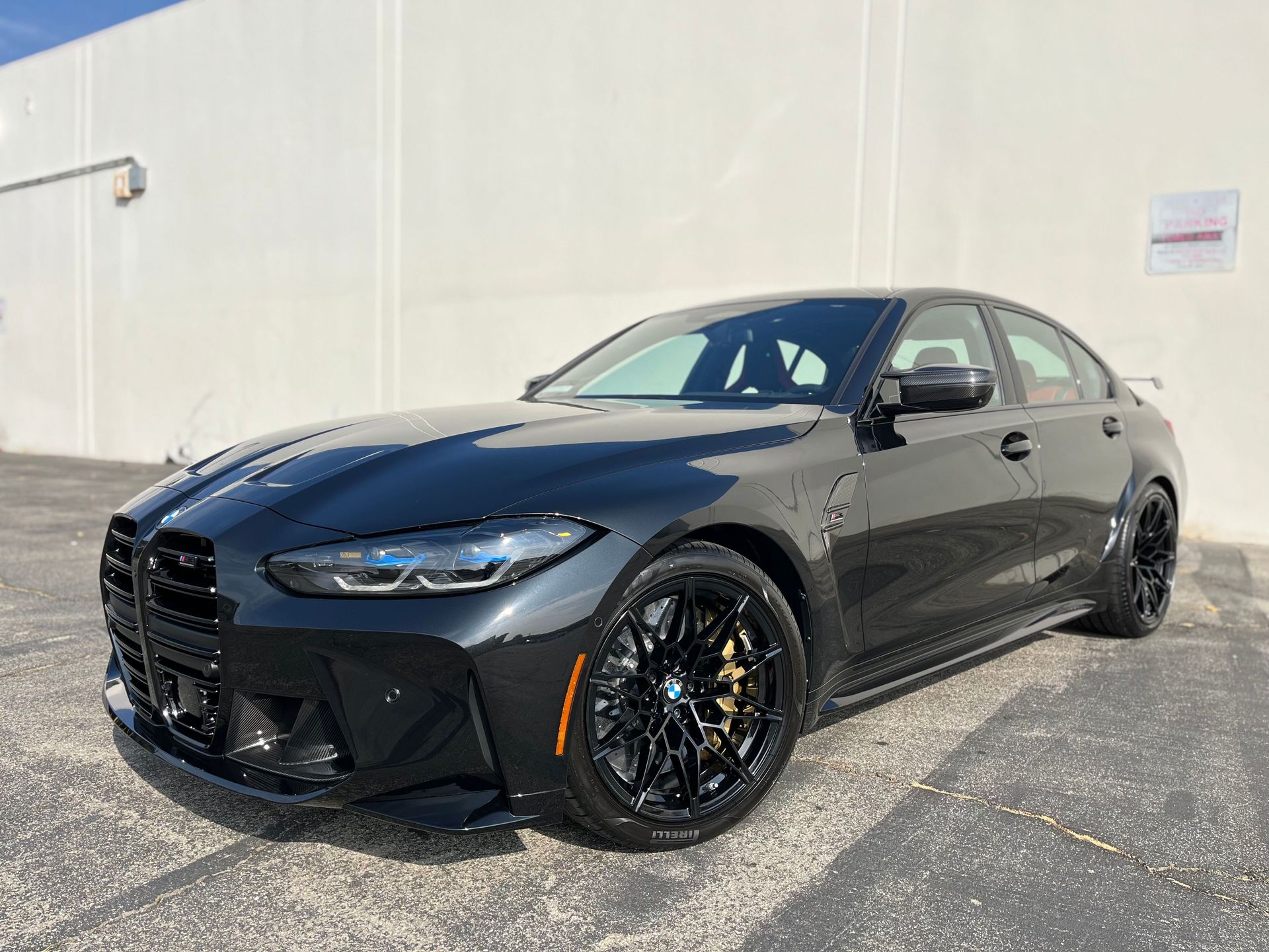 A black bmw m3 is parked in front of a white building.