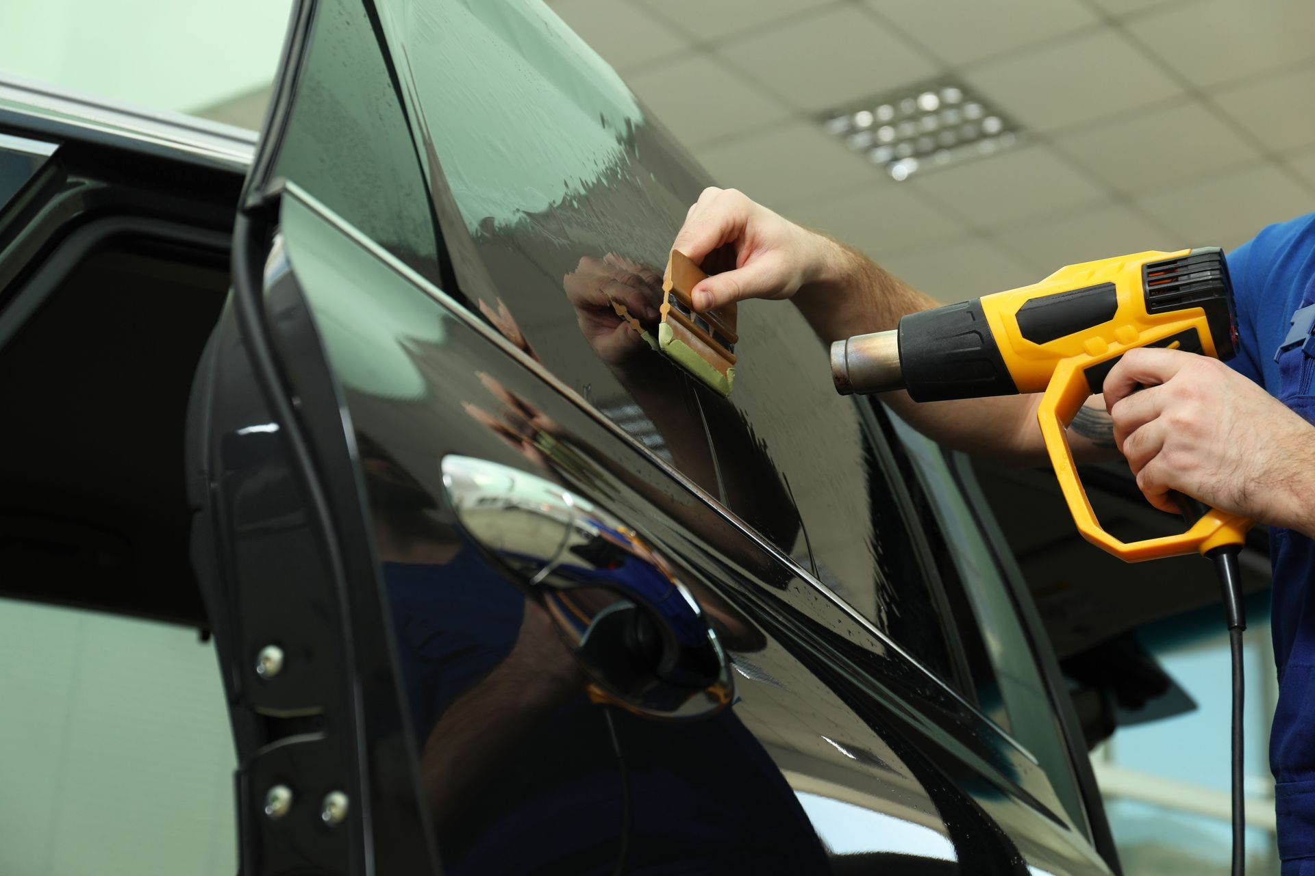 A man is installing window tint to a car