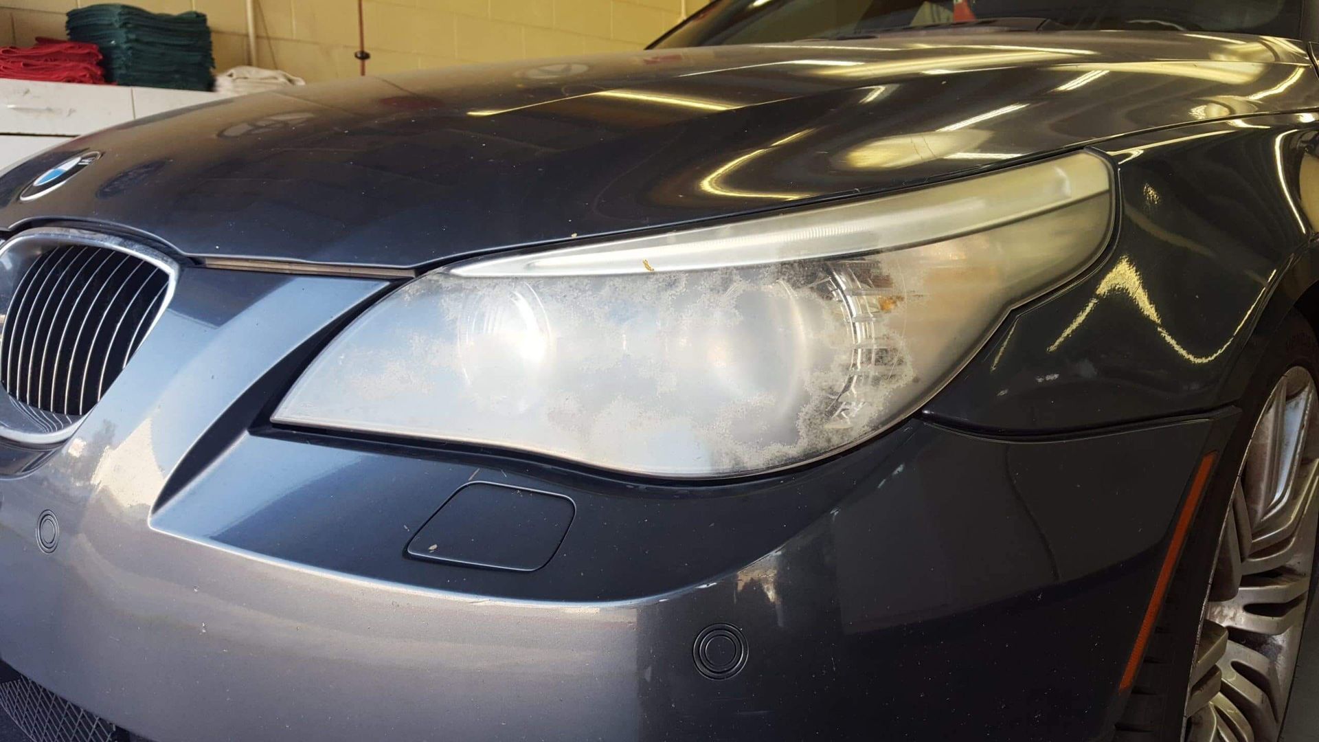 A close up of a car 's headlight in a garage.