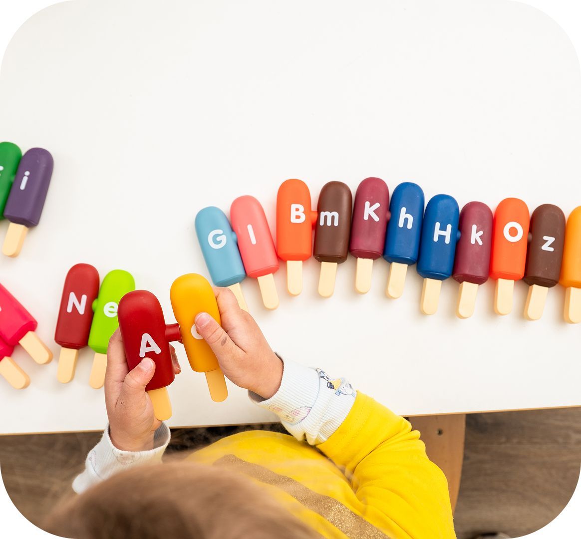 Child learning letters through a hands-on activity at Kinder Academy