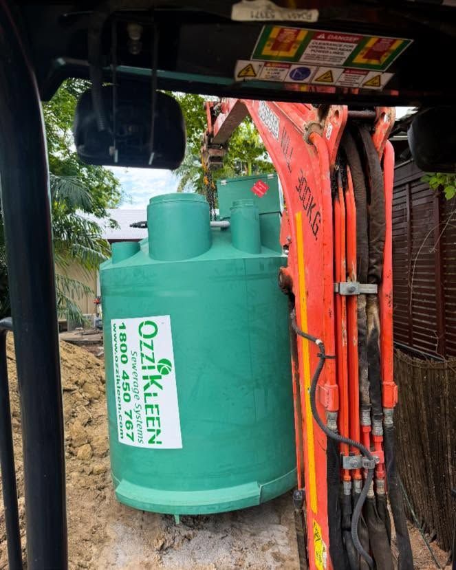 Green industrial tank beside orange equipment under a vehicle or canopy.