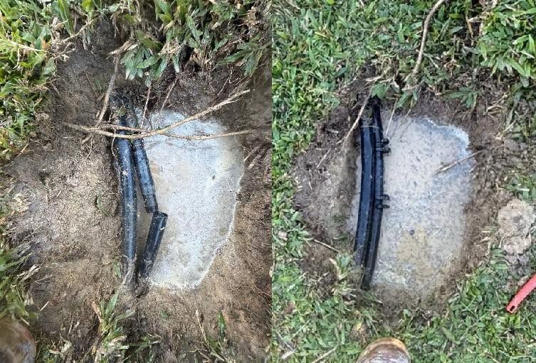 Two black pipes in a small concrete patch beside grass and dirt, shown from above.