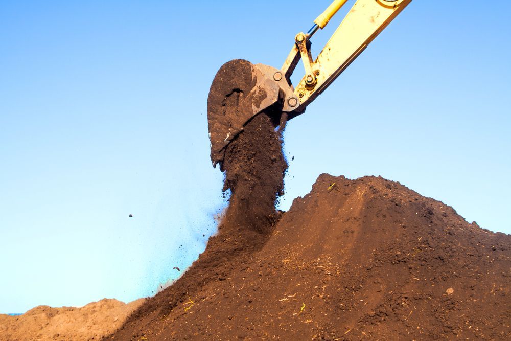 A Large Pile of Dirt is Being Scooped Up by an Excavator — Hoges Plumbing In Kiama, NSW