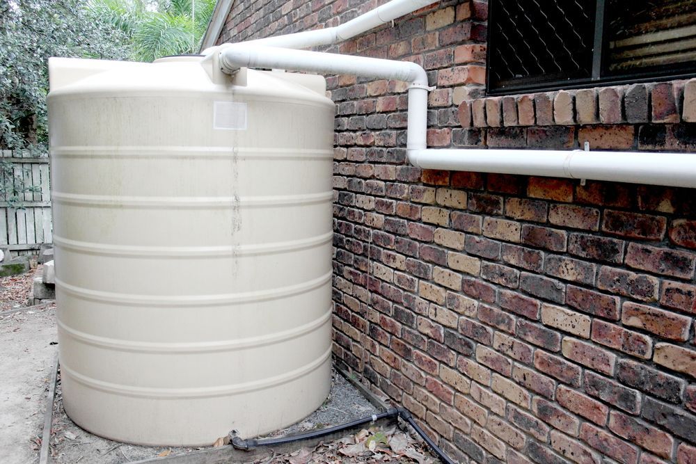 A Gray Water Heater is Attached to a Brick Wall — Hoges Plumbing In West Wollongong, NSW