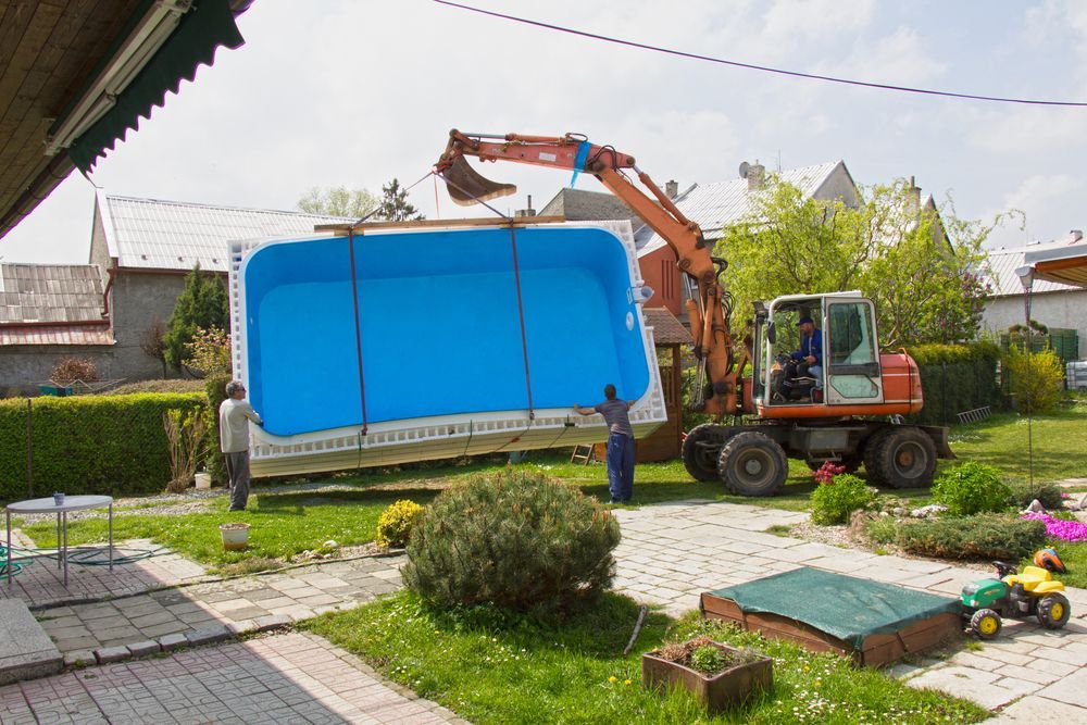 A blue swimming pool is sitting in a pile of sand.
