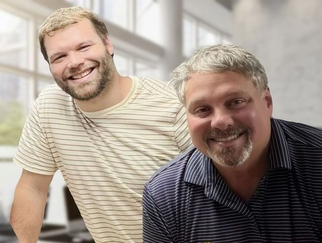 Two smiling men leaning toward the camera in a bright office setting