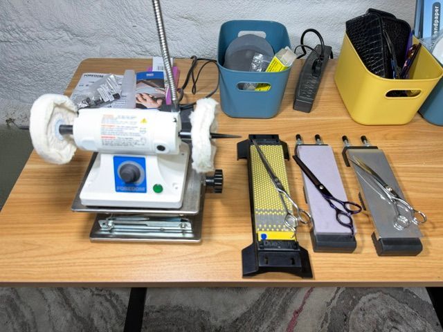 Workbench with a small motorized grinder, trays, and several hand tools on a wooden table.