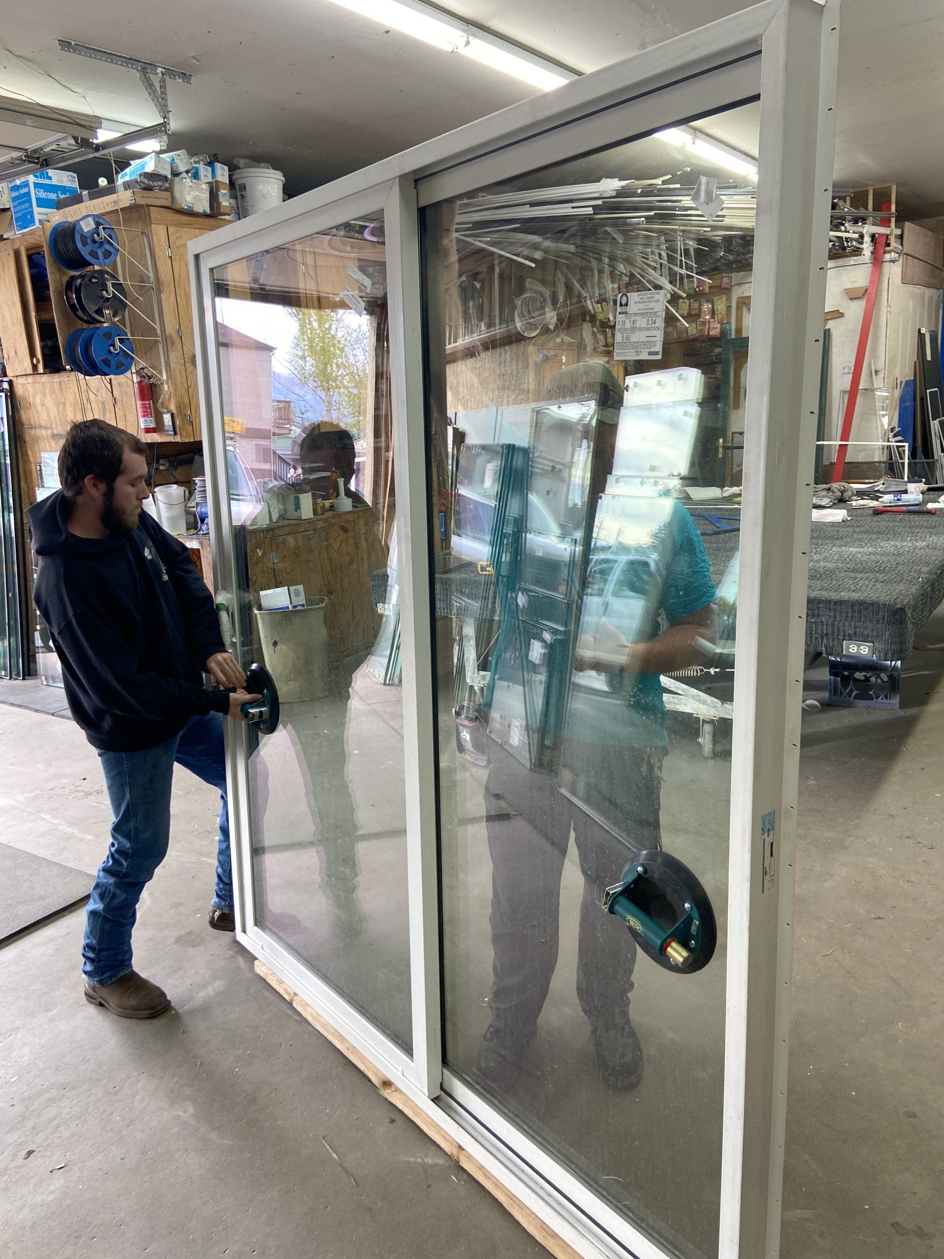 A man is standing next to a large glass door in a room.