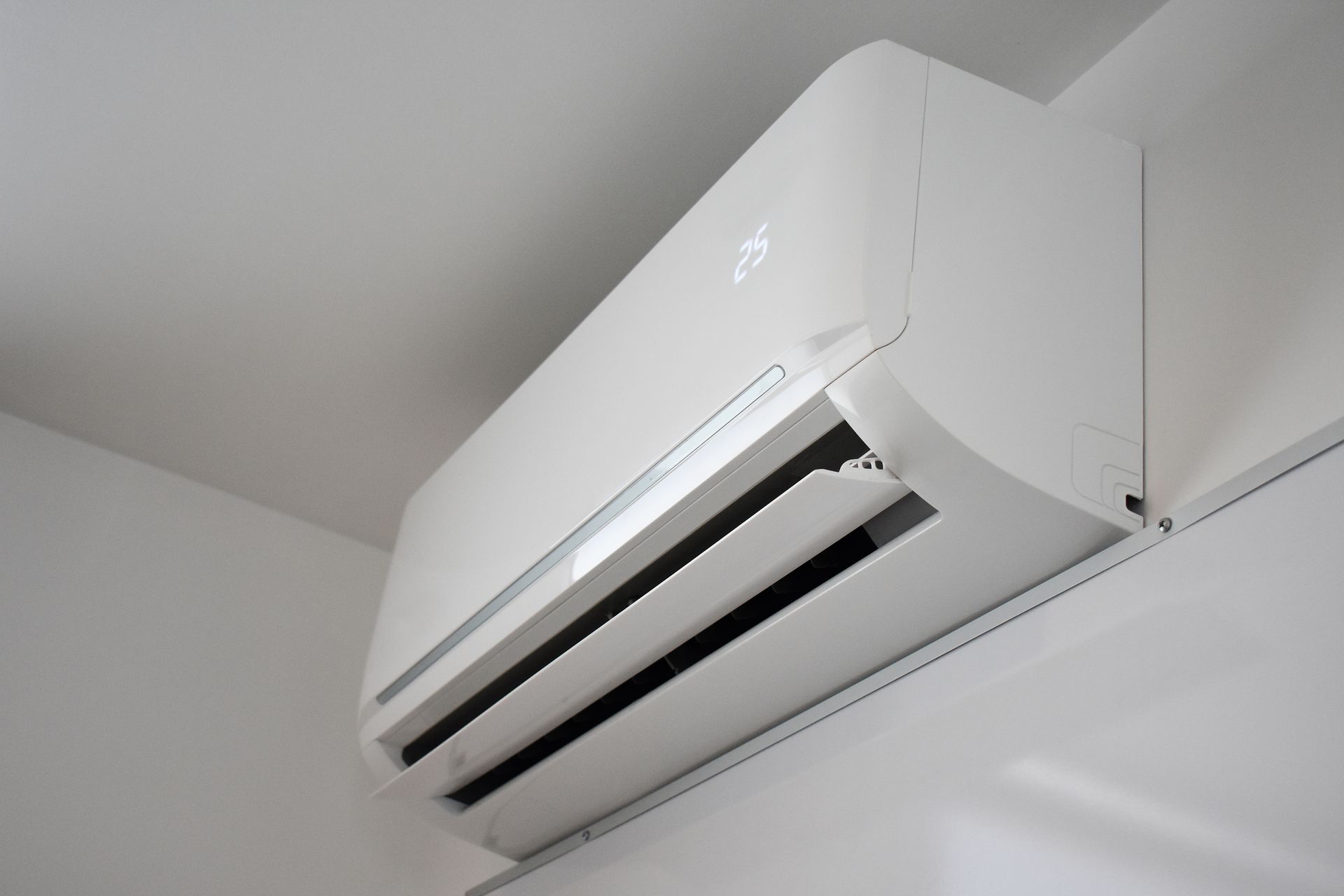 White wall-mounted air conditioner near the ceiling in a room corner