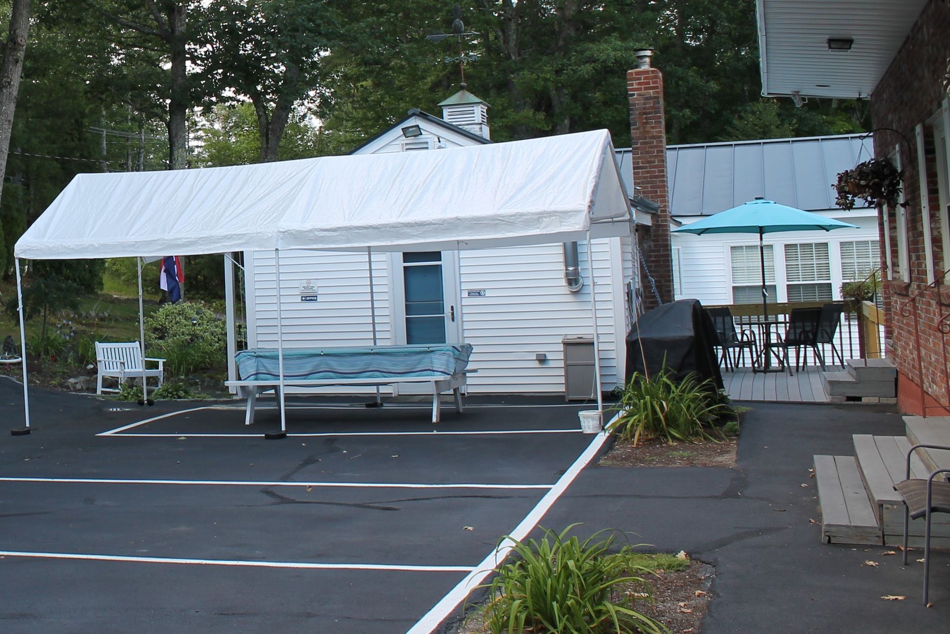 A small white building with a canopy over a picnic table in a parking lot.