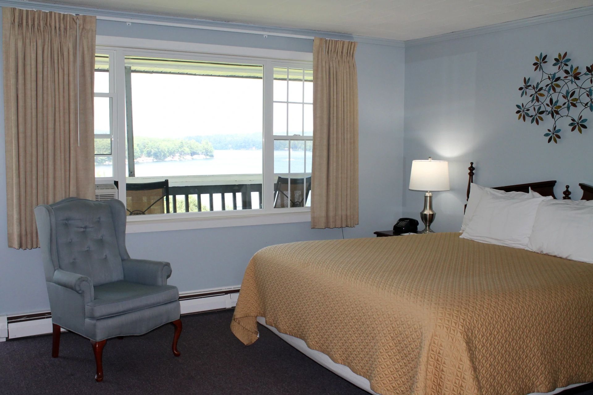 Hotel bedroom with a bed, armchair, window with a view, and decorative wall art.