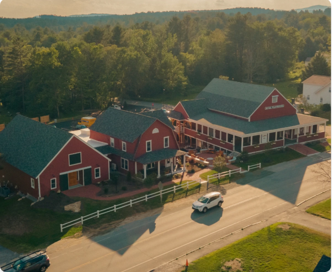 Red buildings, possibly a restaurant, with a car driving in front. Trees in the background.