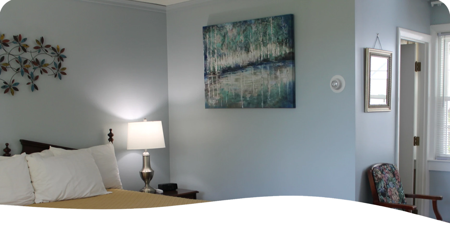 Bedroom corner with a bed, artwork, and a doorway. The walls are light blue.