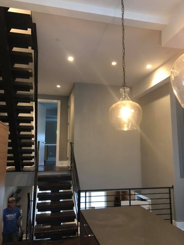 Modern stairwell interior with a hanging glass pendant light and black metal staircase railings.