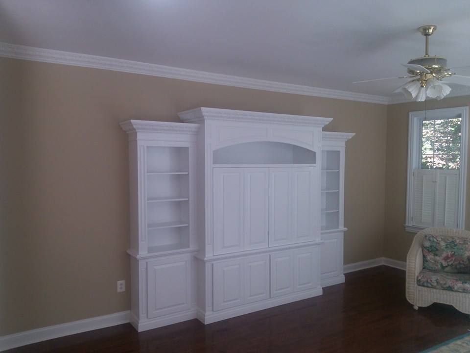 White built-in cabinet against tan walls in an empty room with dark wood floors