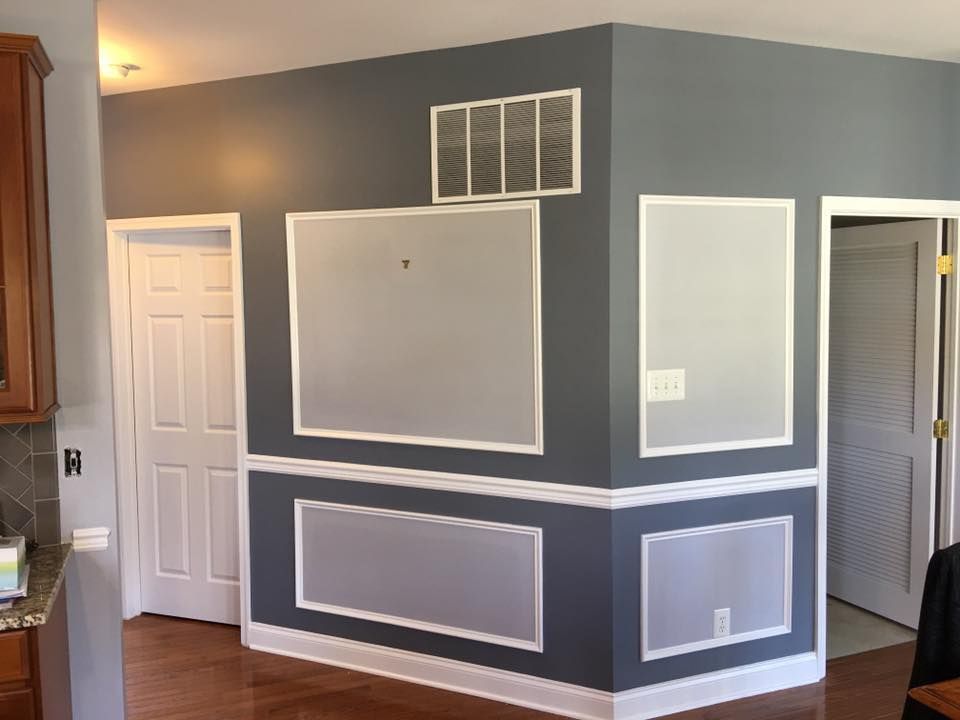 Gray dining room with white trim and decorative wall molding, viewed from an open doorway.
