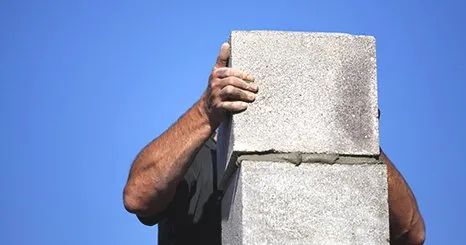 A man is holding a concrete block in front of his face.