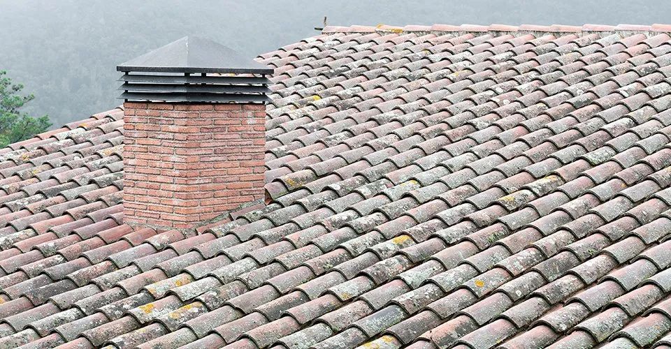 A brick chimney on top of a tiled roof.