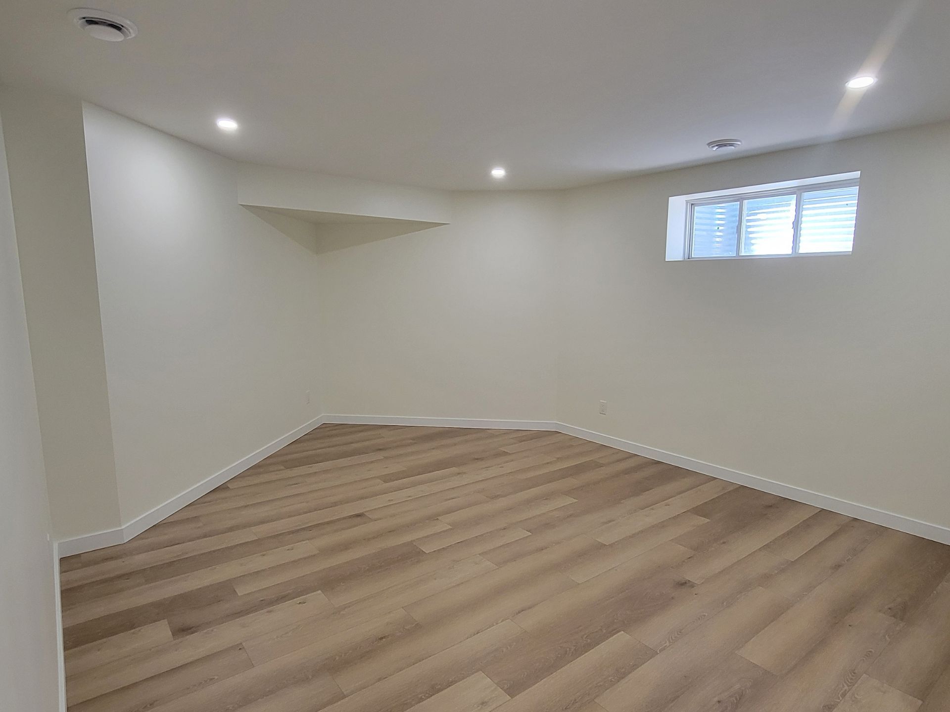The same basement living room finished with drywall, flooring, and pot lights by Alpha-Omega Developments