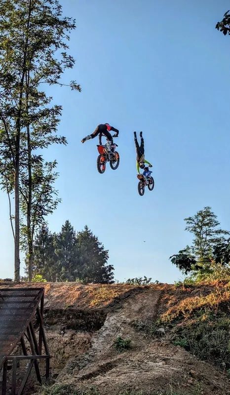 Due piloti di motocross a mezz'aria sopra un salto di terra, contro un cielo azzurro La Varesina Emergenza Varese