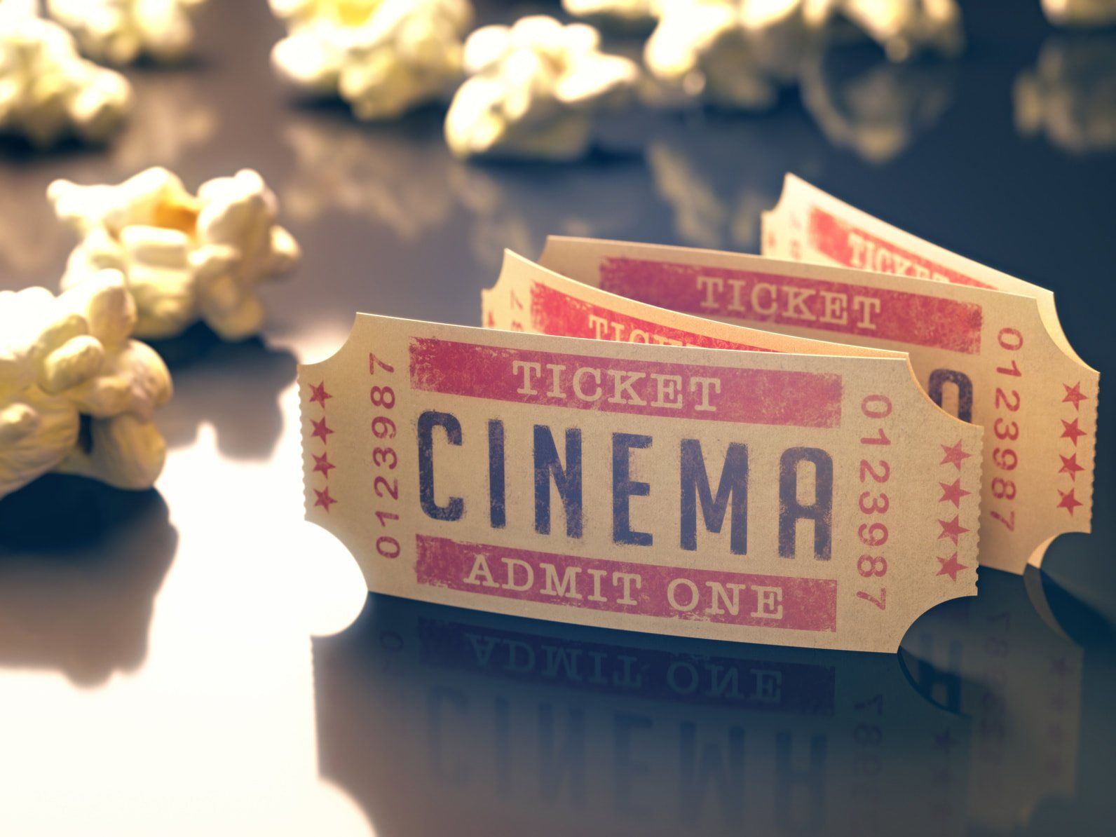 Three vintage cinema tickets with popcorn on a reflective surface.