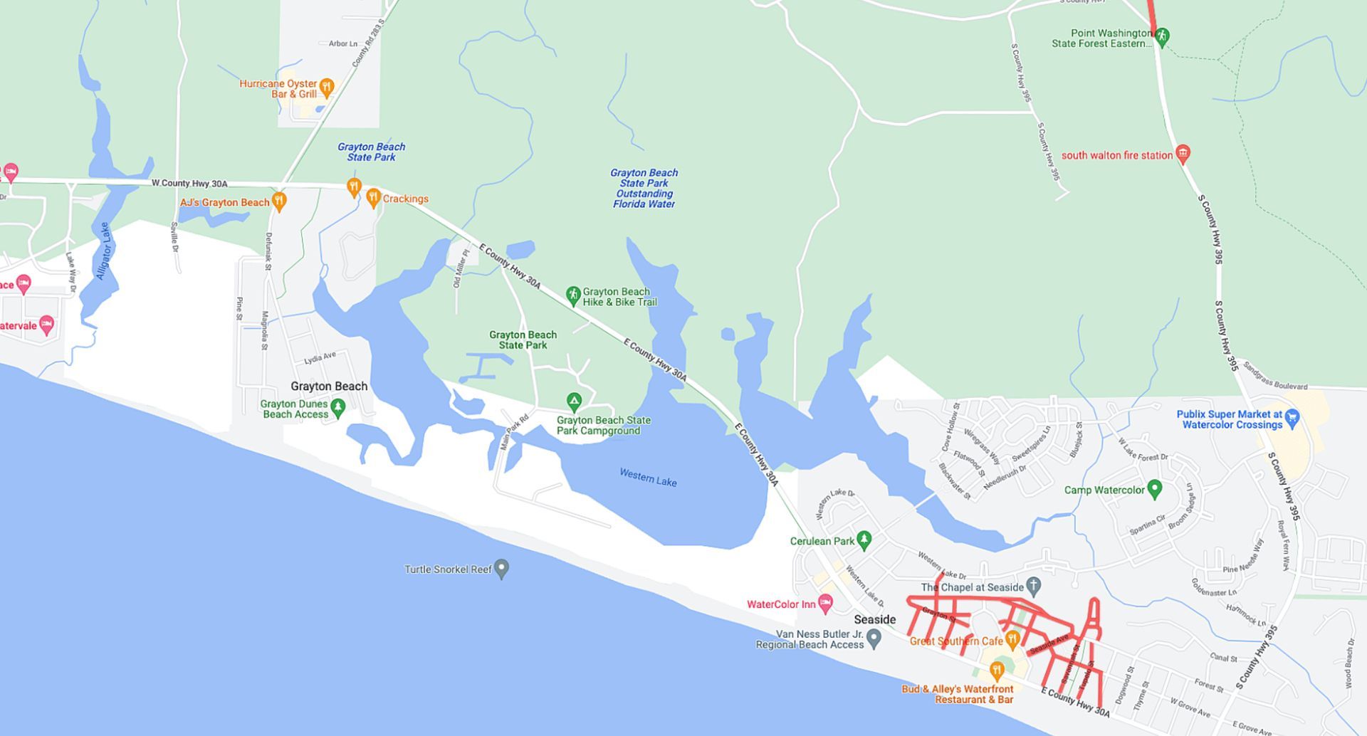 A map of an area featuring a large blue body of water along a coastline, surrounded by green land and residential streets.