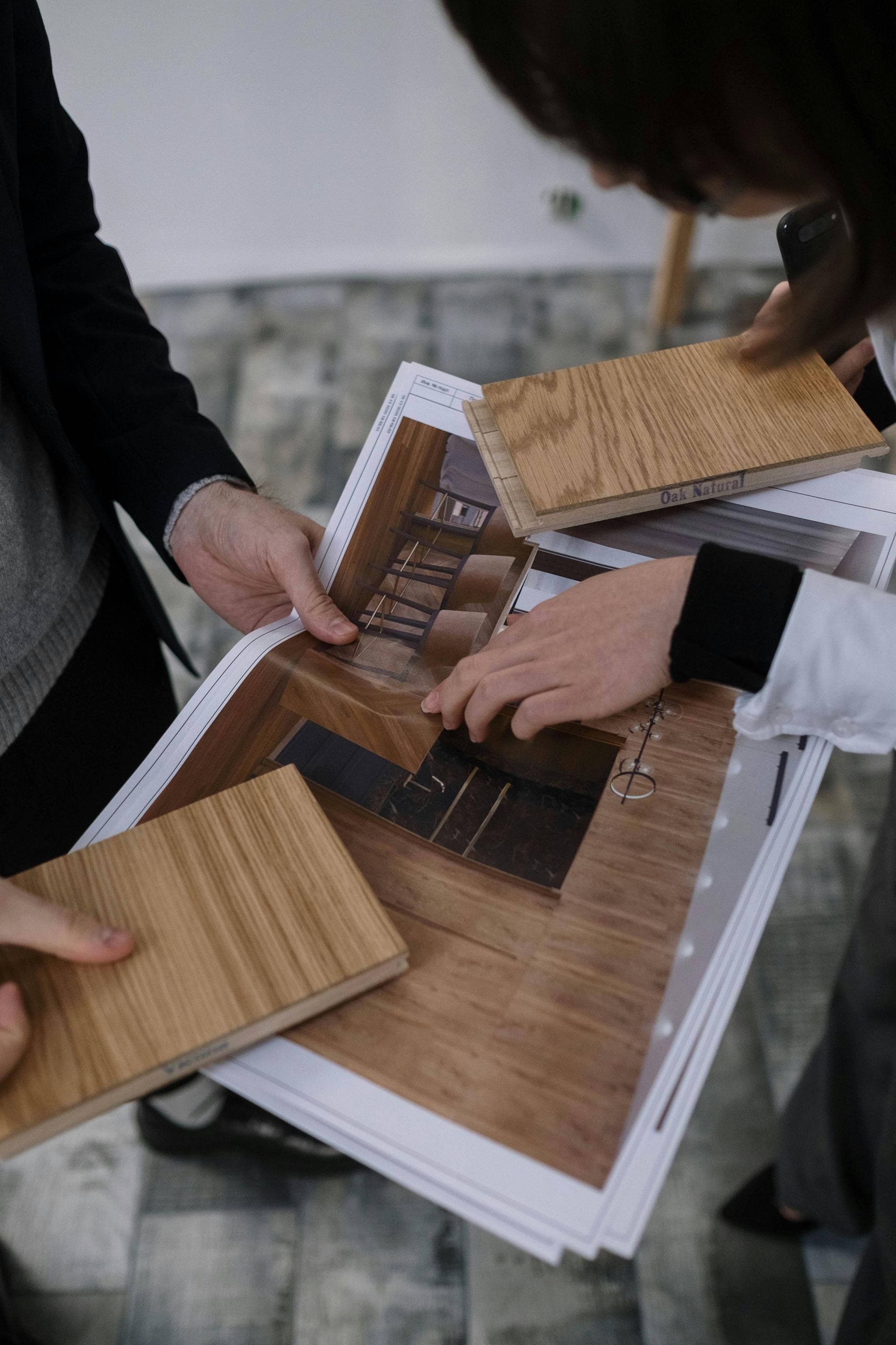 Des personnes examinant des échantillons de revêtements de sol et des plans de conception, dans un cadre intérieur.