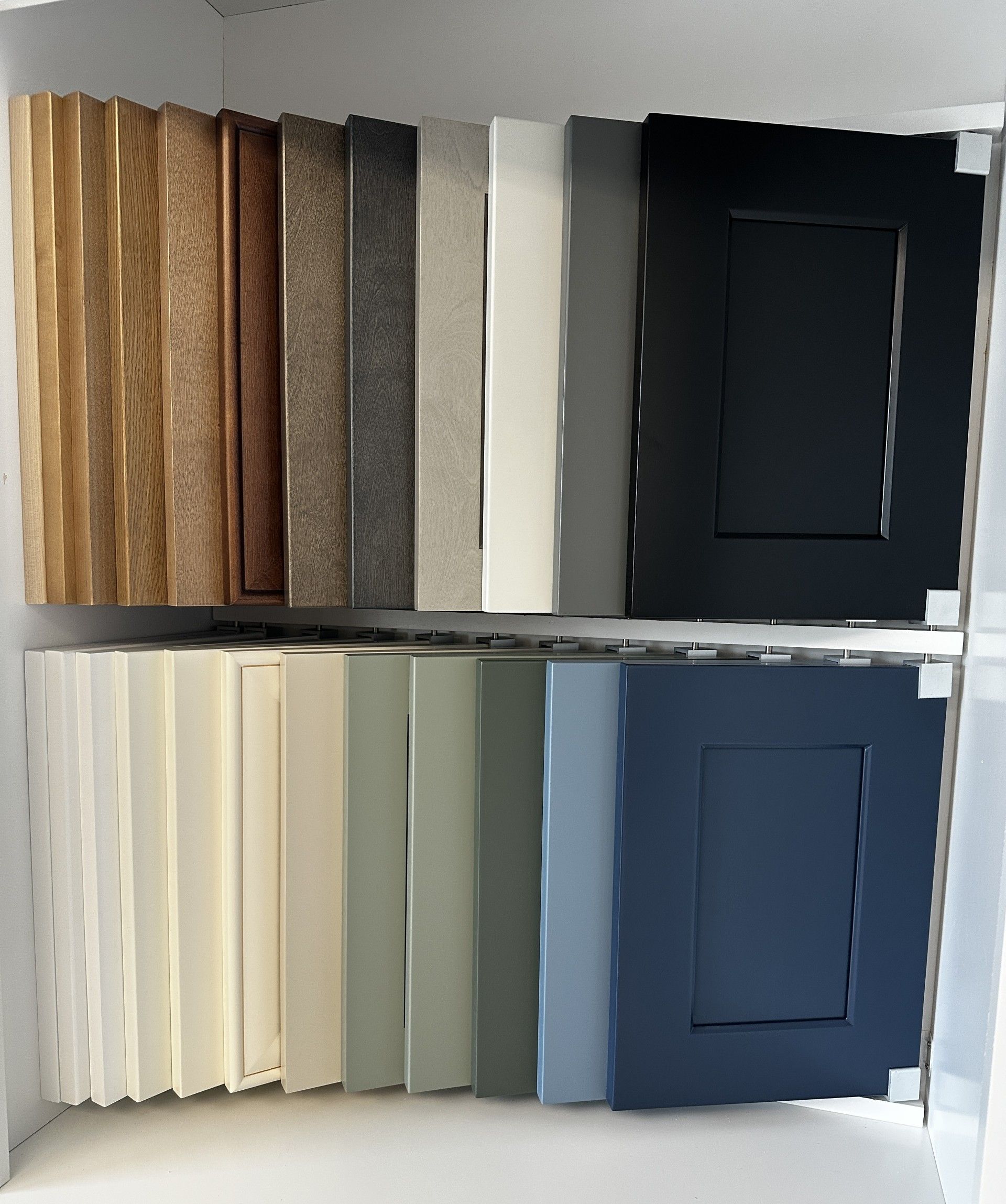 Shelves displaying fabric or paint samples in neutral and dark colors, arranged in two rows