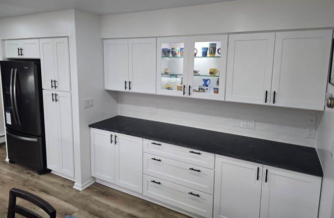 White kitchen cabinets with black countertops and appliances.