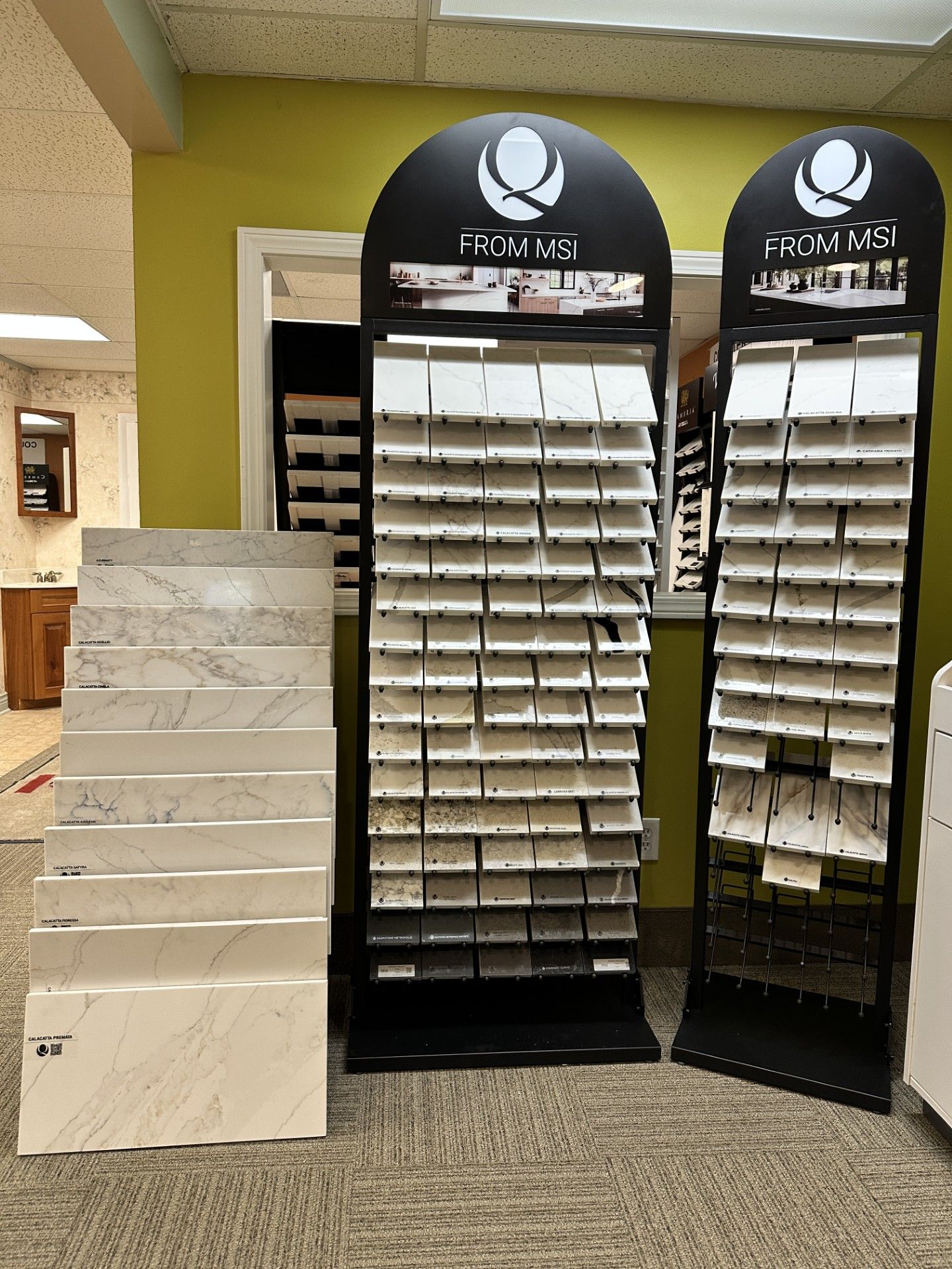 Tile and countertop samples on display in a showroom, arranged on stands.