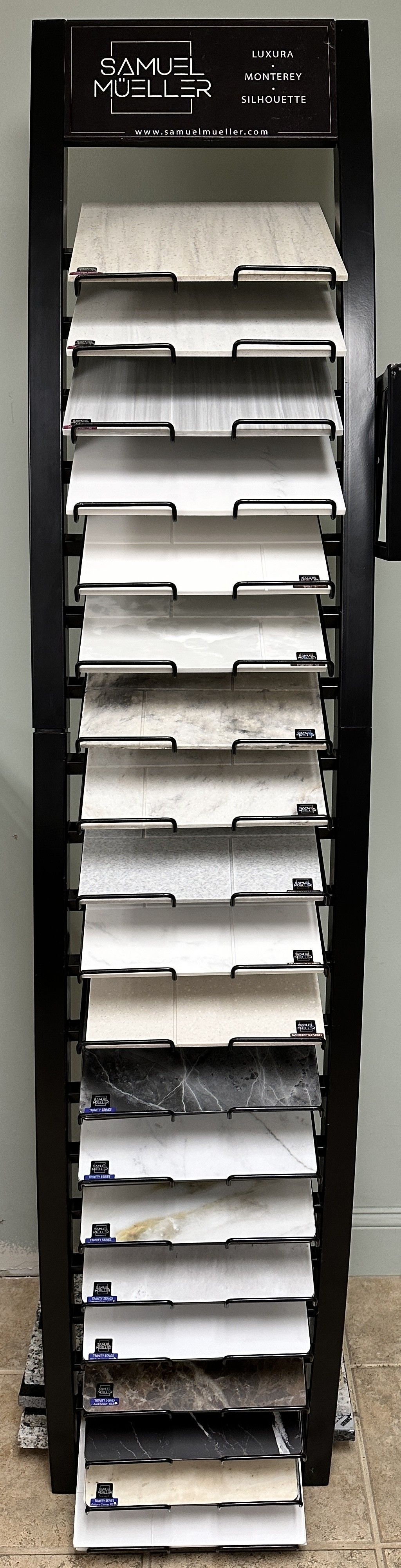 A tall black display rack filled with tile samples of various colors and textures.