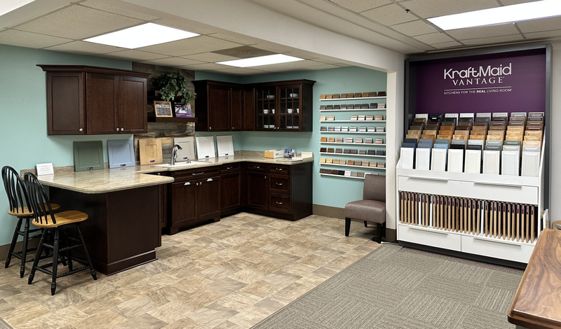 Interior of a kitchen showroom with cabinetry, countertop samples, and a color selection display.
