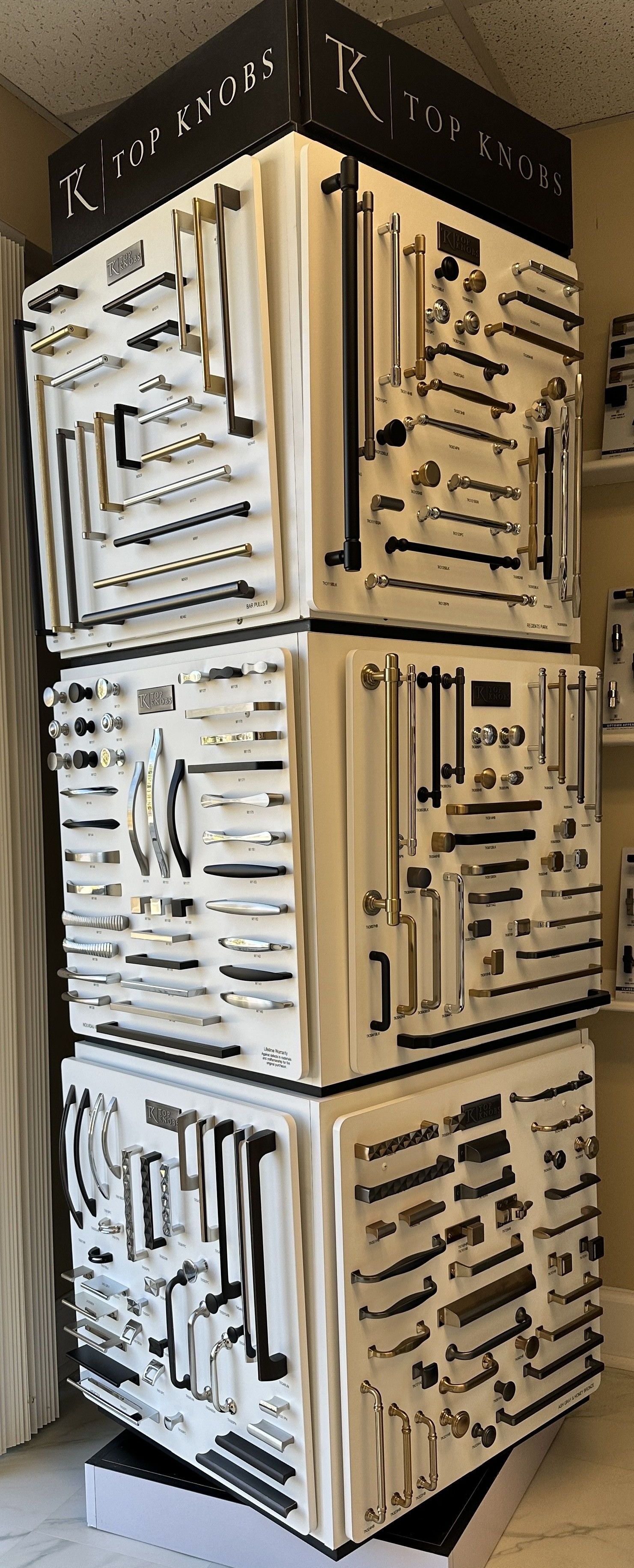 Display of cabinet hardware on stacked white cubes in a store.
