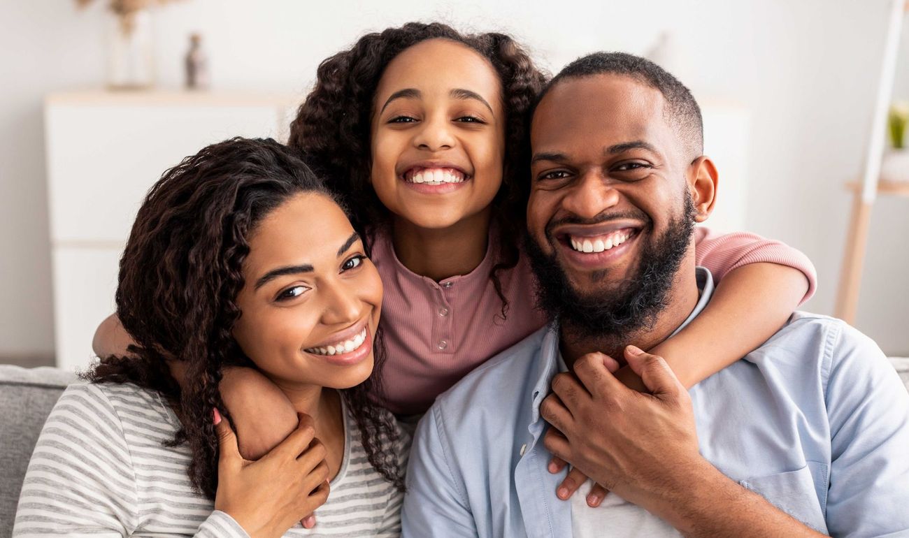 A family is posing for a picture together while sitting on a couch.