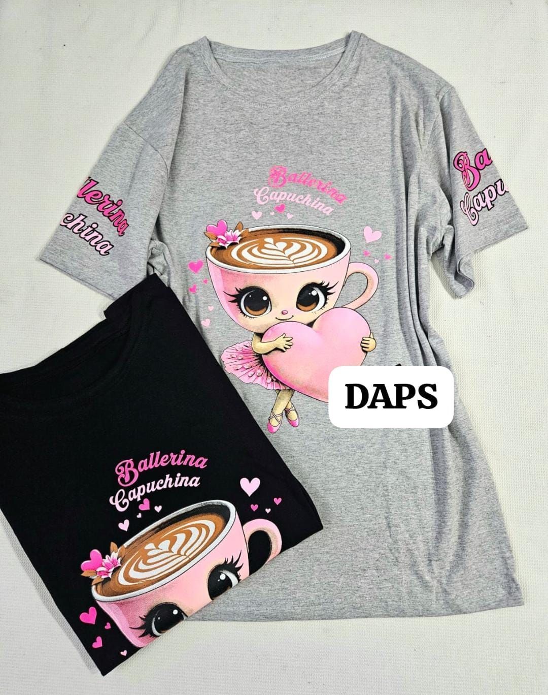 Dos camisetas, una gris y otra negra, estampadas con un dibujo de una bailarina capuchino.