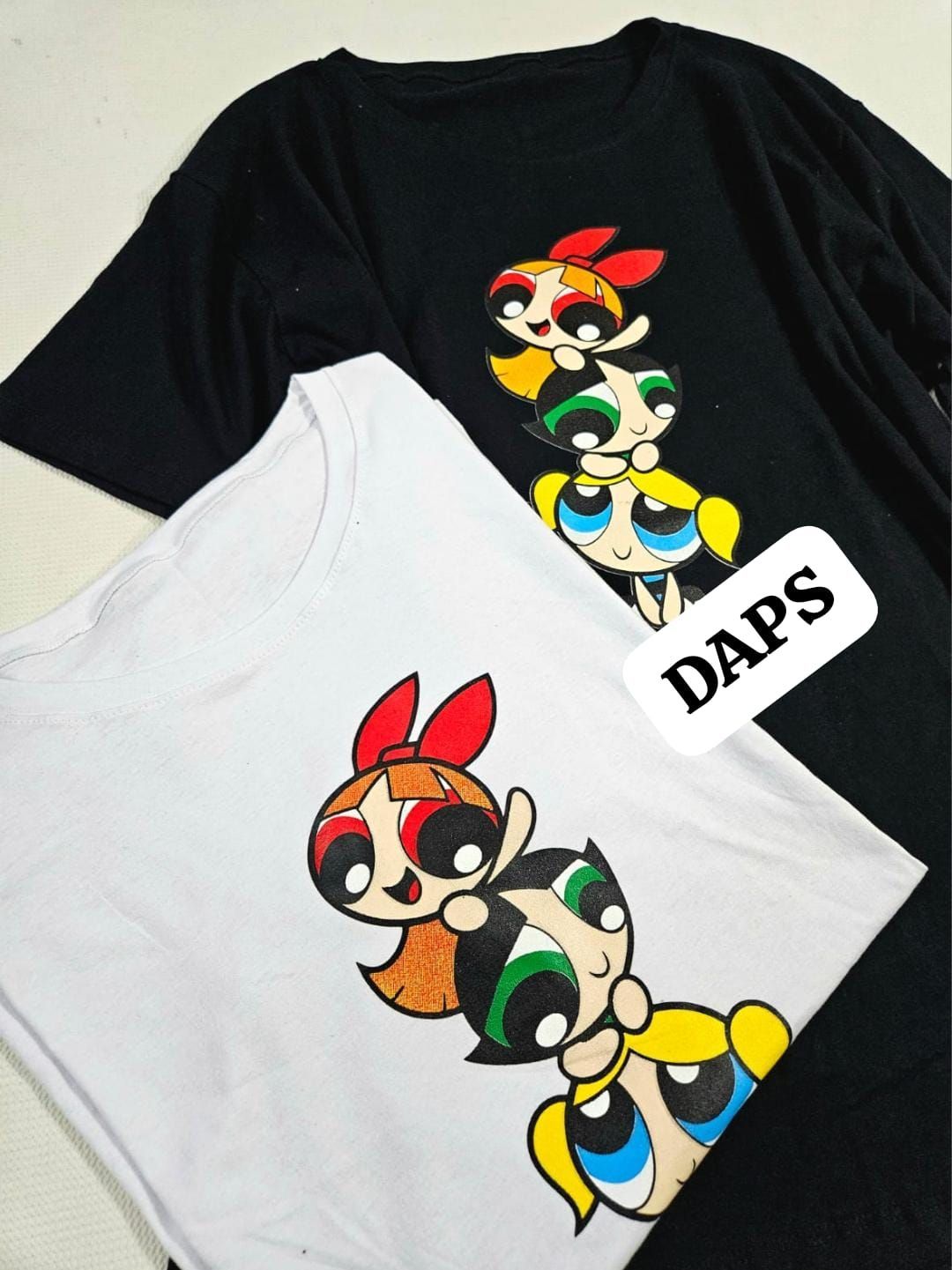 Dos camisetas: una blanca y otra negra, cada una con un diseño de dibujos animados de las Chicas Superpoderosas.