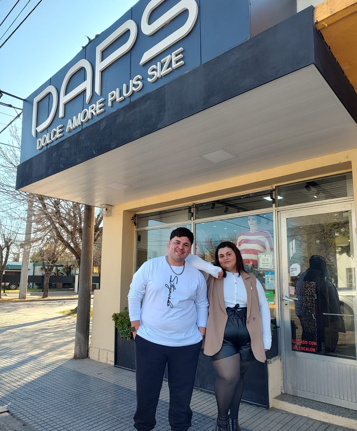 Dos personas están de pie frente a una tienda de ropa llamada 