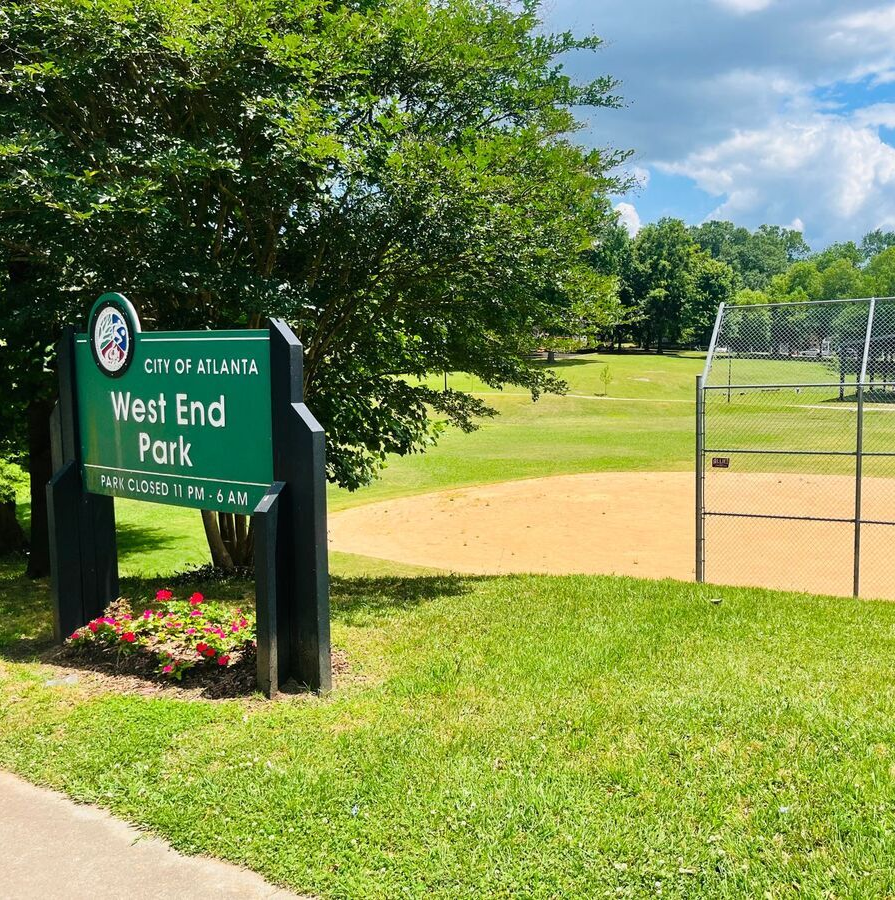 West End Park sign beside a baseball field and green lawn on a sunny day